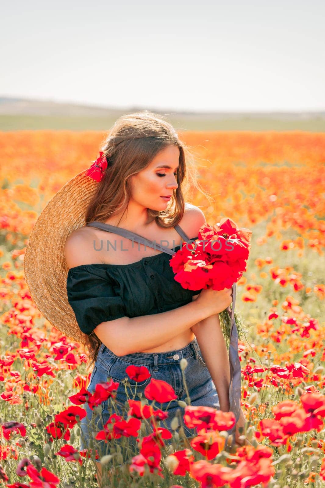 Woman poppies field. portrait of a happy woman with long hair in a poppy field and enjoying the beauty of nature in a warm summer day