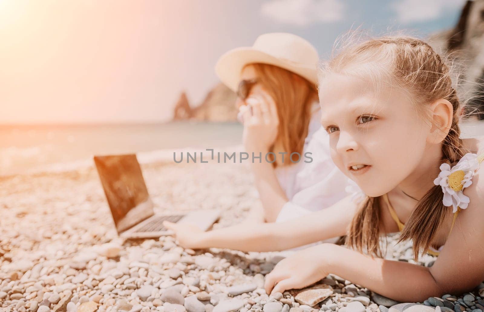 Woman sea laptop. Business woman with daughter, working on laptop by sea. Close up on hands of pretty lady typing on computer outdoors summer day. Freelance, digital nomad, travel and holidays concept by panophotograph