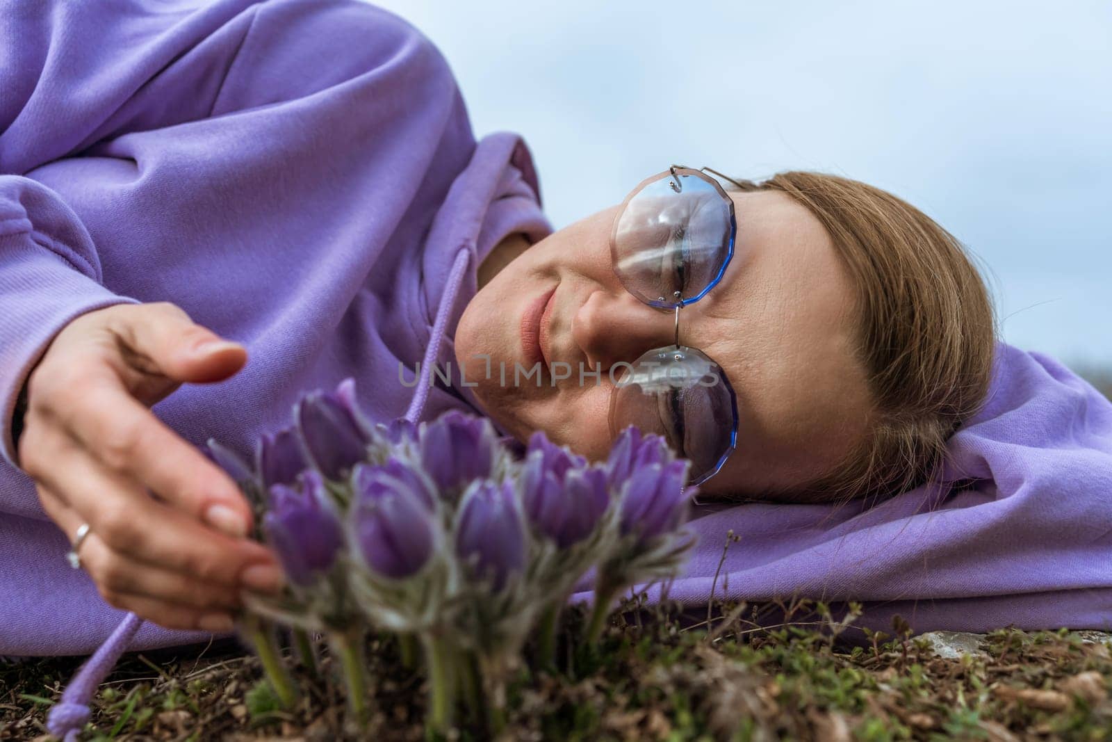 Dream grass woman spring flower. Woman lies on the ground and hugs flowers pasqueflower or Pulsatilla Grandis flowers.