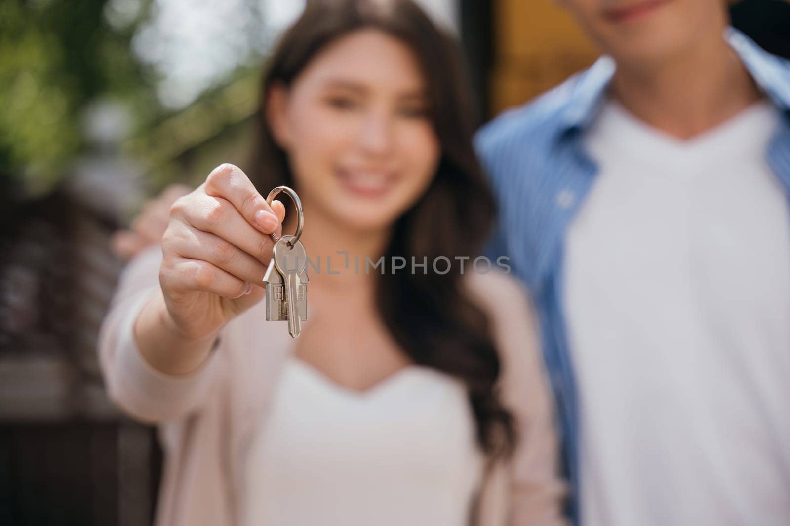 A successful home relocation is captured as a couple displays keys while carrying a mattress. Their happiness echoes the joy of moving in real estate. Moving Day Concept
