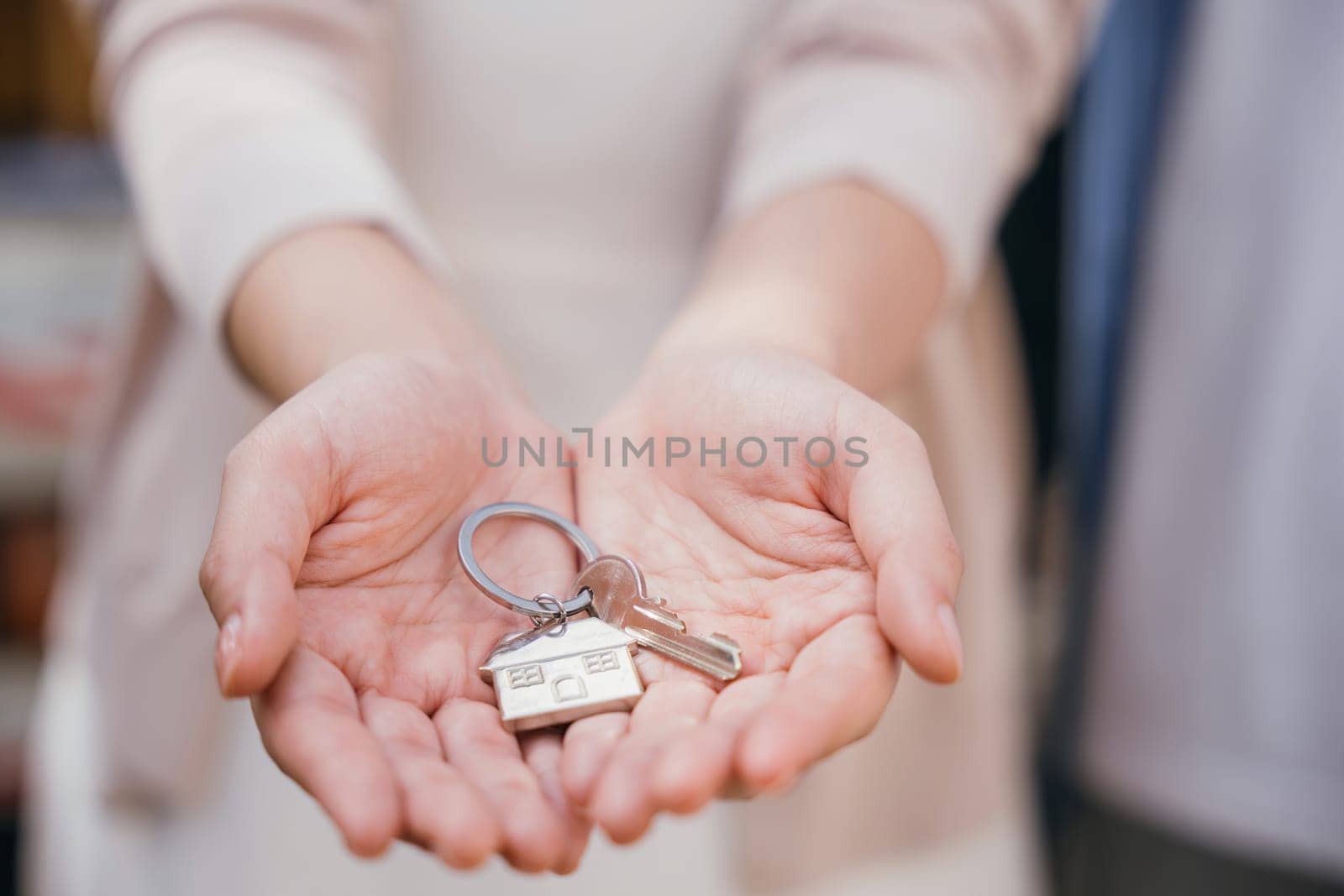 Happy woman a landlord hands keys signifying new home buy. Real estate concept close-up portrays success security and tenant happiness. Landlord's hand gives keys to the camera. Give me the key