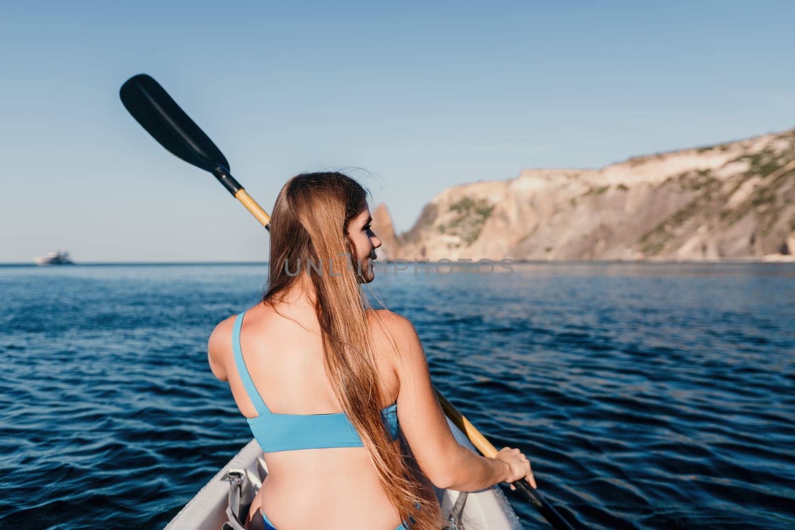 Woman in kayak back view. Happy young woman with long hair floating in kayak on calm sea. Summer holiday vacation and cheerful female people relaxing having fun on the boat. by panophotograph