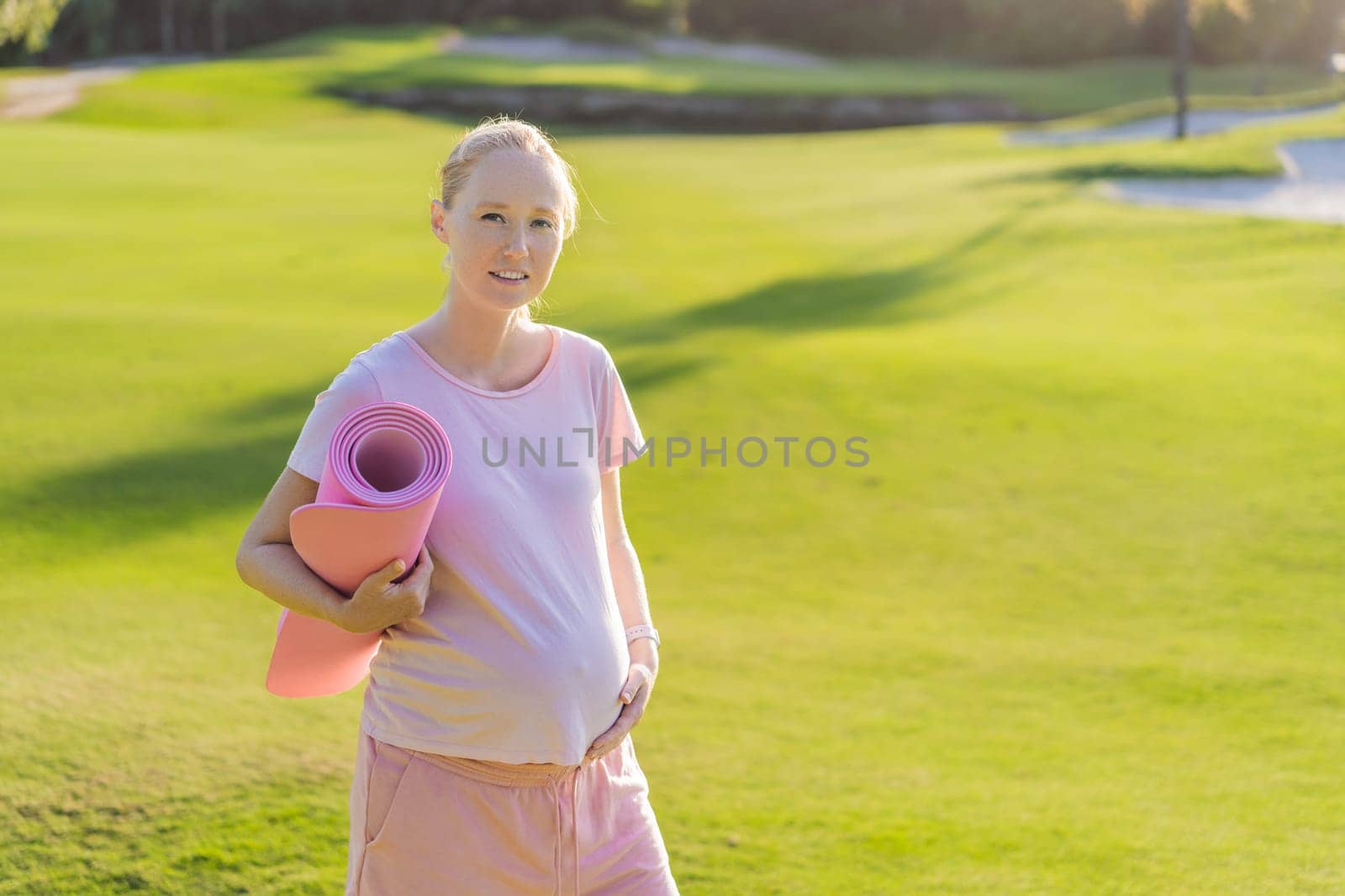 Energetic pregnant woman takes her workout outdoors, using an exercise mat for a refreshing and health-conscious outdoor exercise session by galitskaya