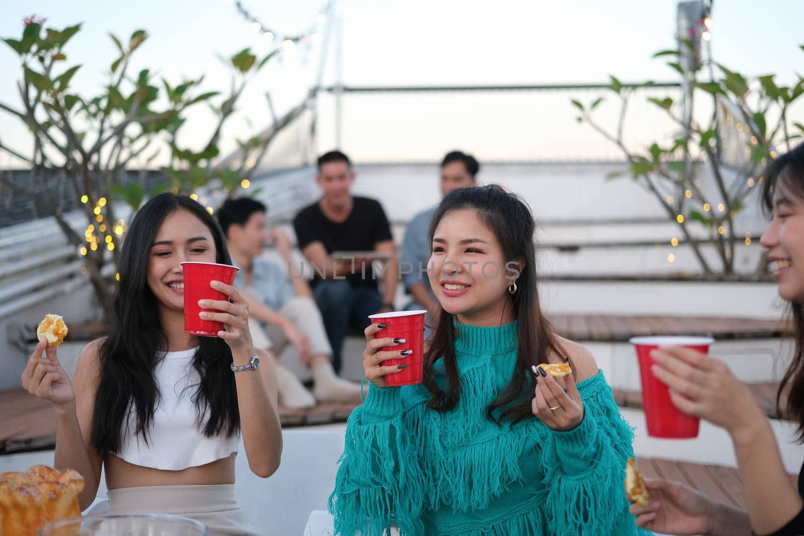 Cheerful young people having fun chatting together at a rooftop party