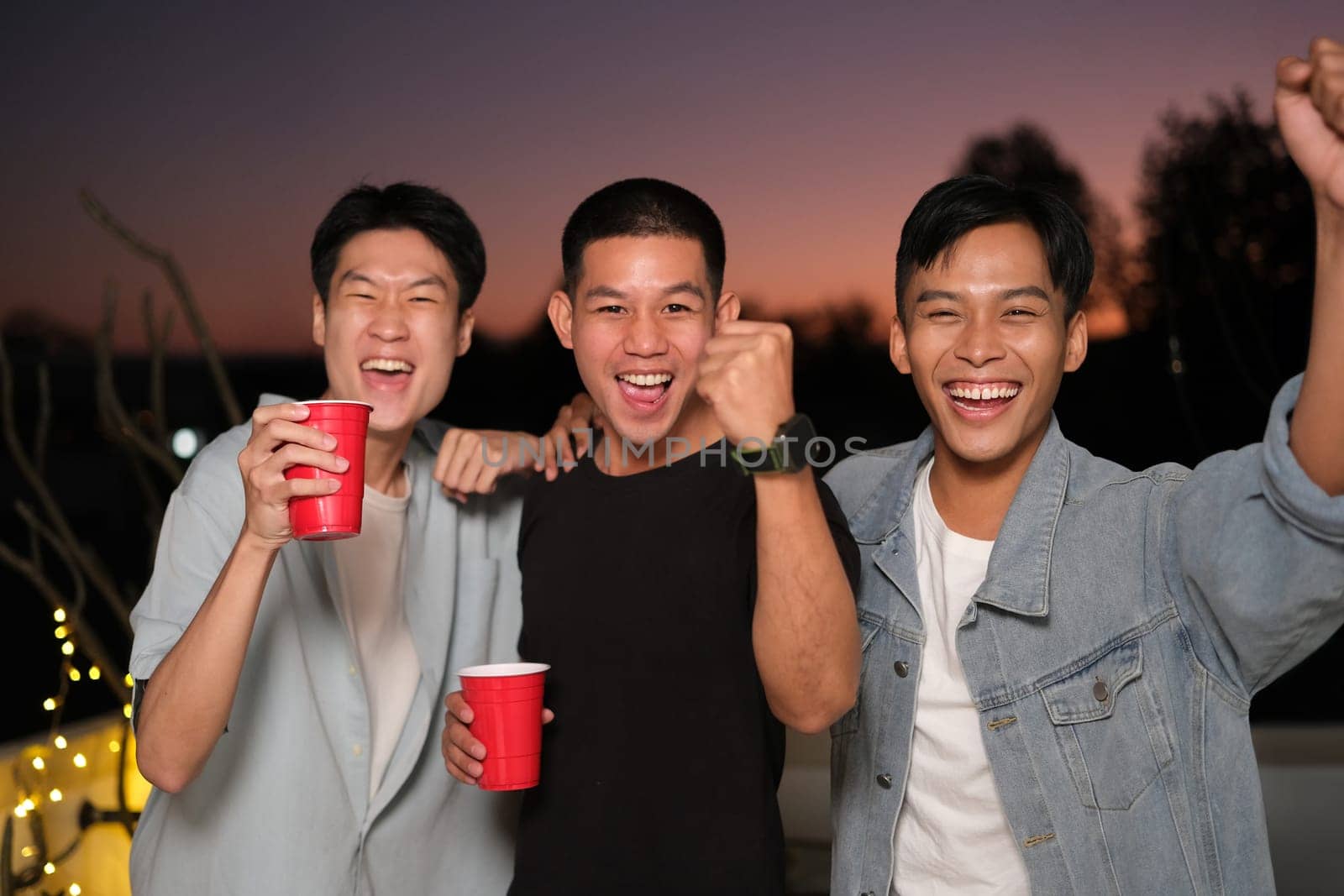 Group of young friends laughing and having fun at rooftop party