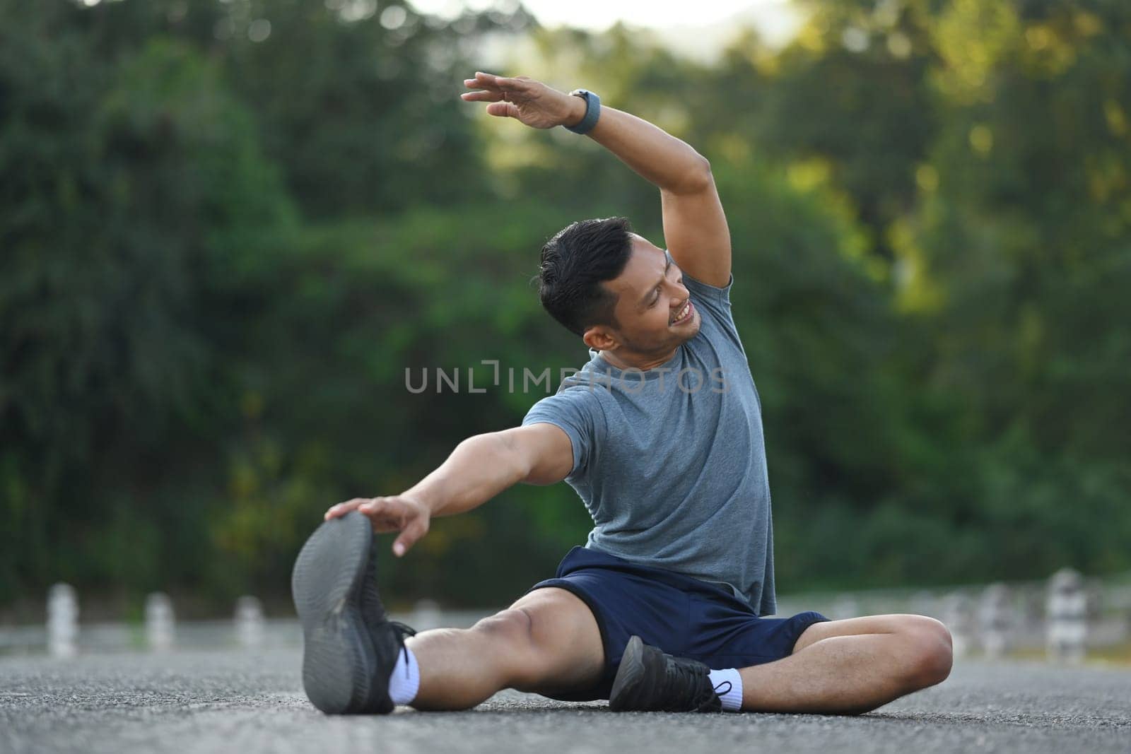 Athletic man stretching his muscular before before running in the morning. Fitness, sport and healthy lifestyle concept. by prathanchorruangsak