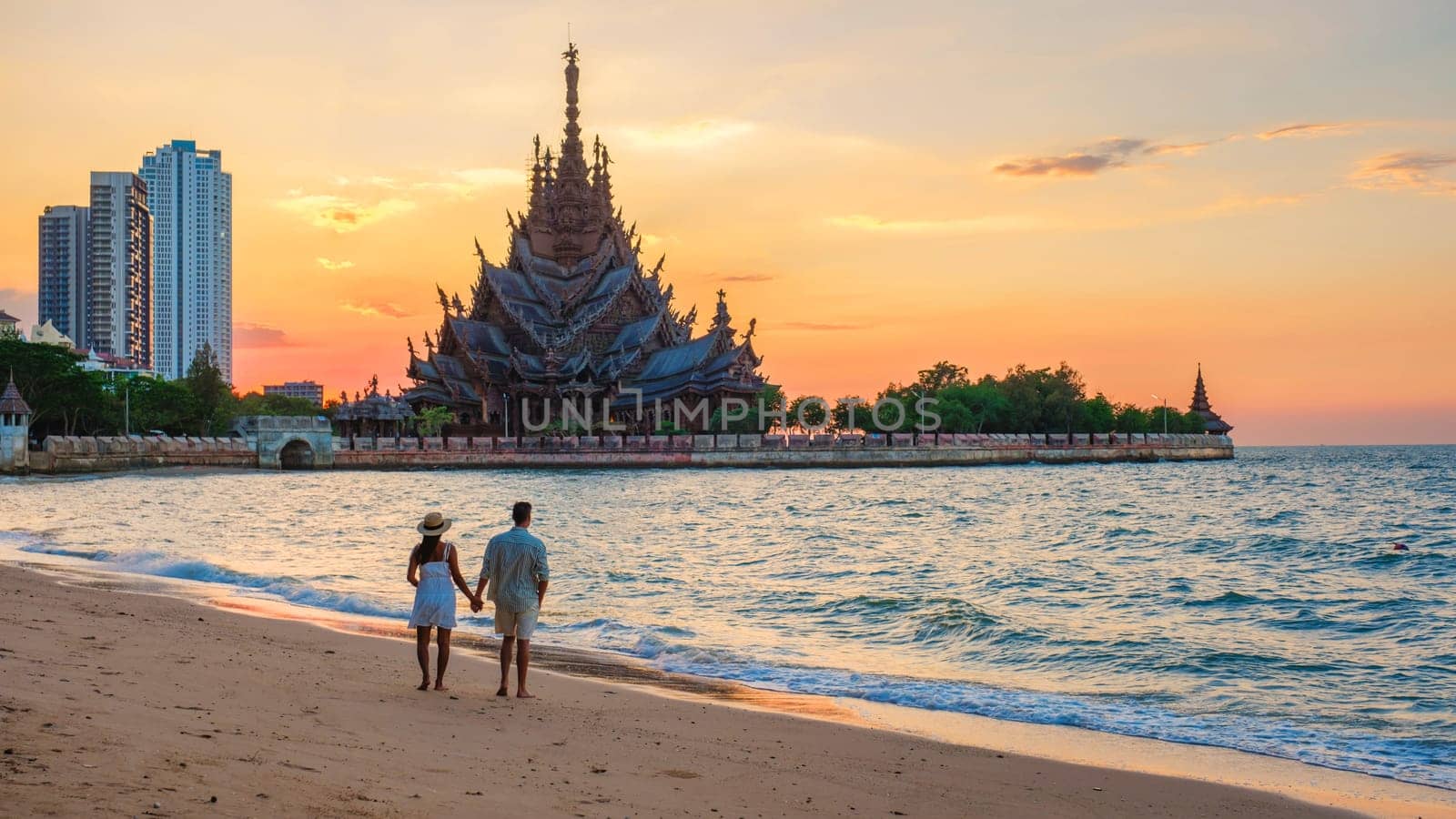 A diverse multiethnic couple of men and women visit The Sanctuary of Truth wooden temple in Pattaya Thailand.