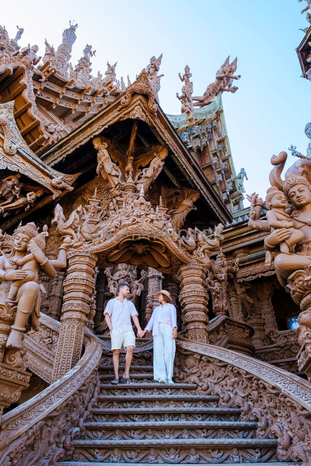 A diverse multiethnic couple of men and women visit The Sanctuary of Truth temple in Pattaya Thailand. It is a wooden temple construction located at the cape of Naklua Pattaya City Chonburi Thailand