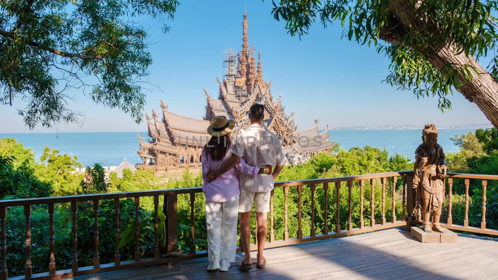 A diverse multiethnic couple of men and women visit The Sanctuary of Truth wooden temple in Pattaya Thailand. a wooden temple located at the cape of Naklua Pattaya City Chonburi Thailand