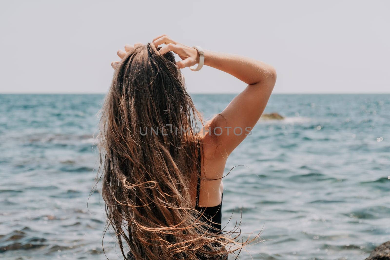 Woman travel sea. Young Happy woman in a long red dress posing on a beach near the sea on background of volcanic rocks, like in Iceland, sharing travel adventure journey