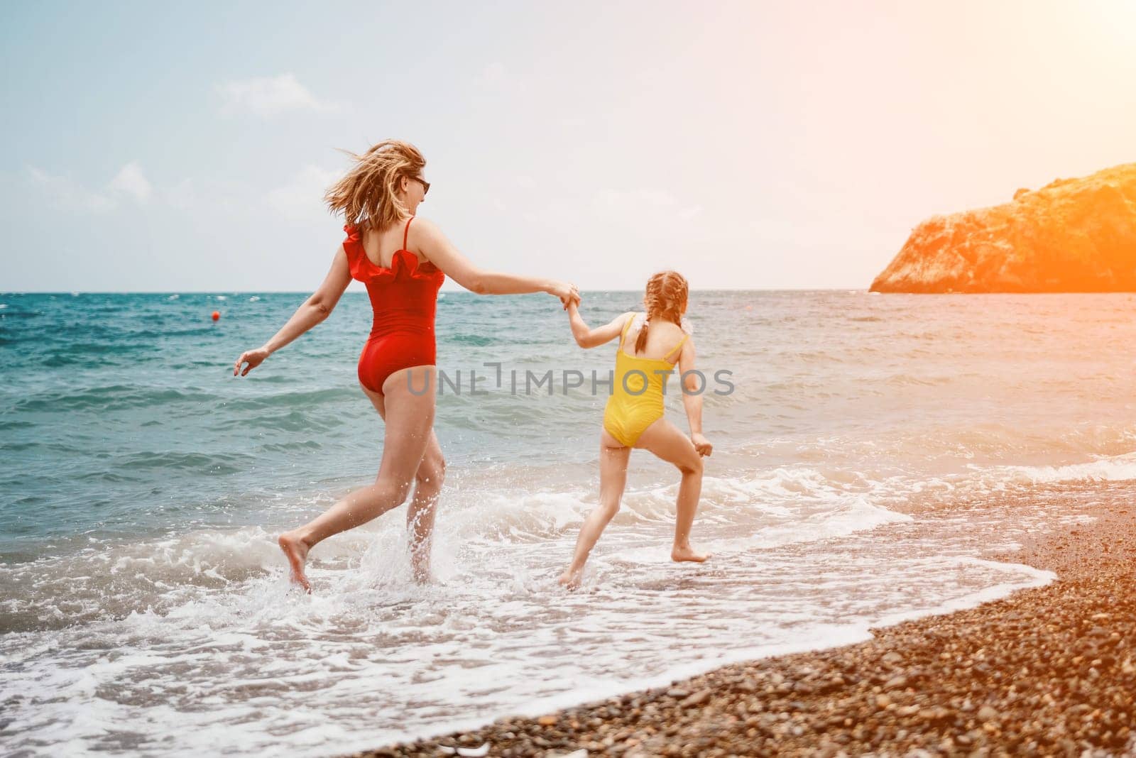 Happy loving family mother and daughter having fun together on the beach. Mum playing with her kid in holiday vacation next to the ocean - Family lifestyle and love concept.