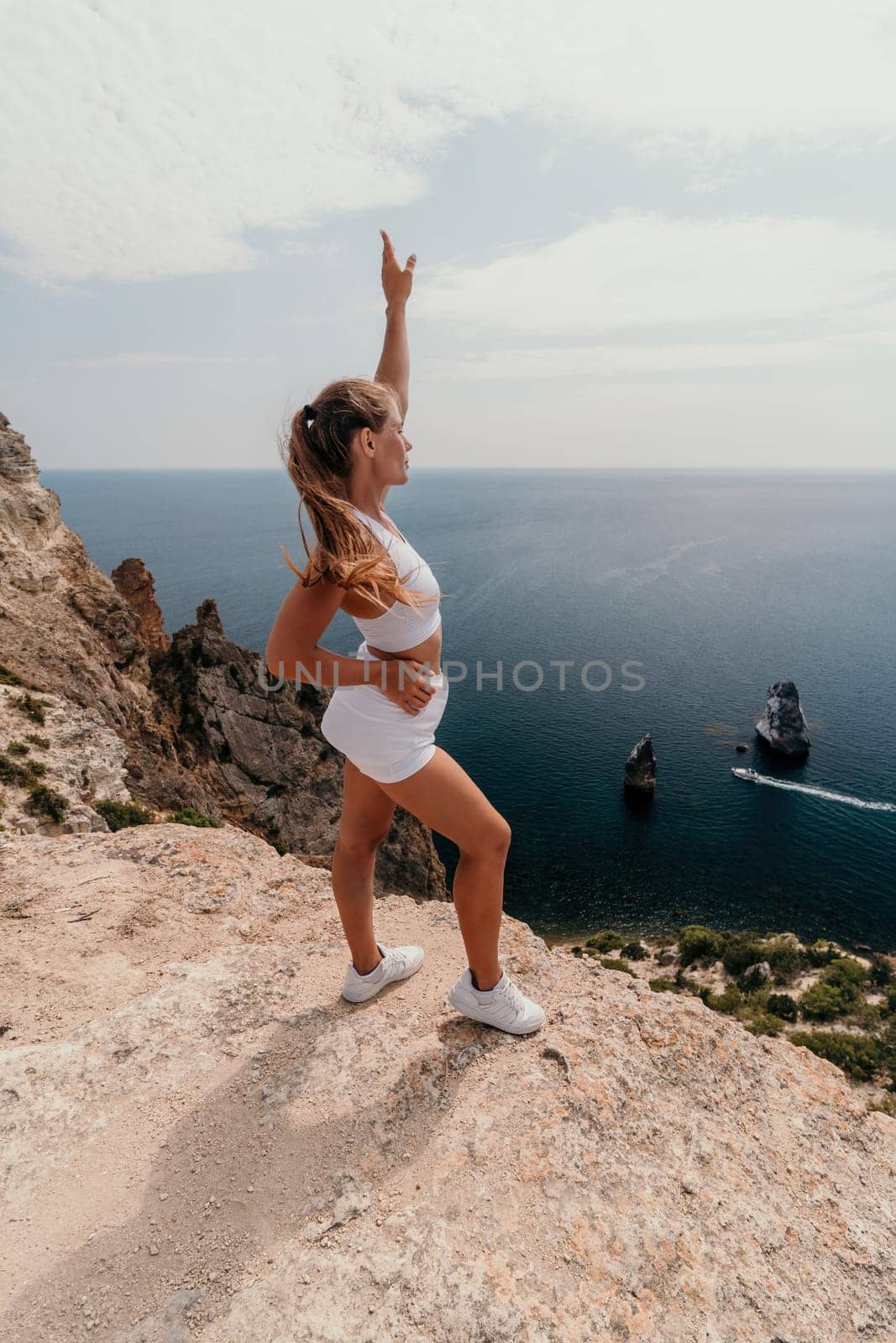 Woman travel sea. Happy tourist in hat enjoy taking picture outdoors for memories. Woman traveler posing on the beach at sea surrounded by volcanic mountains, sharing travel adventure journey