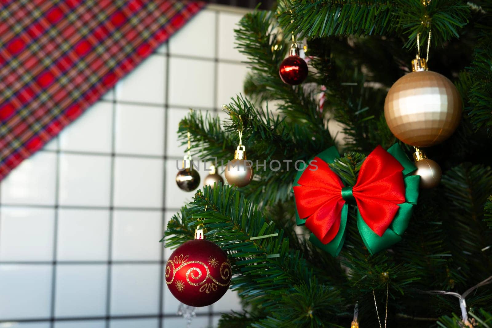 Close up of Christmas tree flashing colors with reflection in window. focus on red bow. Close up of colorful balls for decorating the Christmas tree.