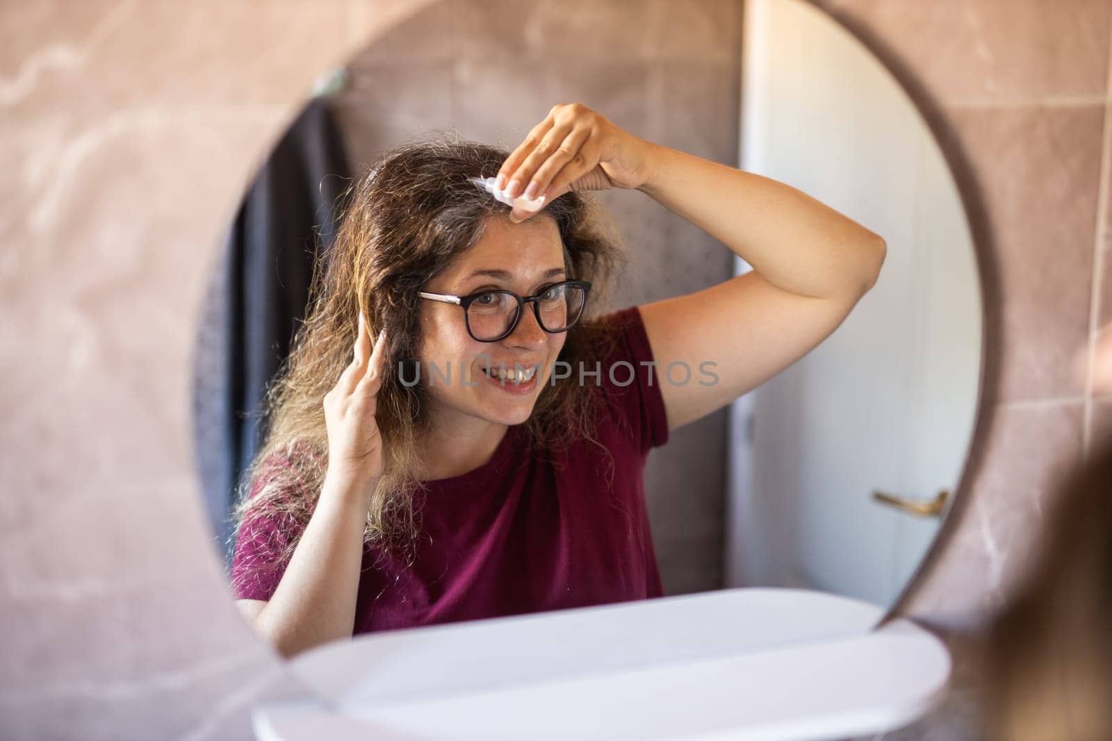 Gray haired surprised caucasian middle aged woman looking at grey hair head in mirror reflection