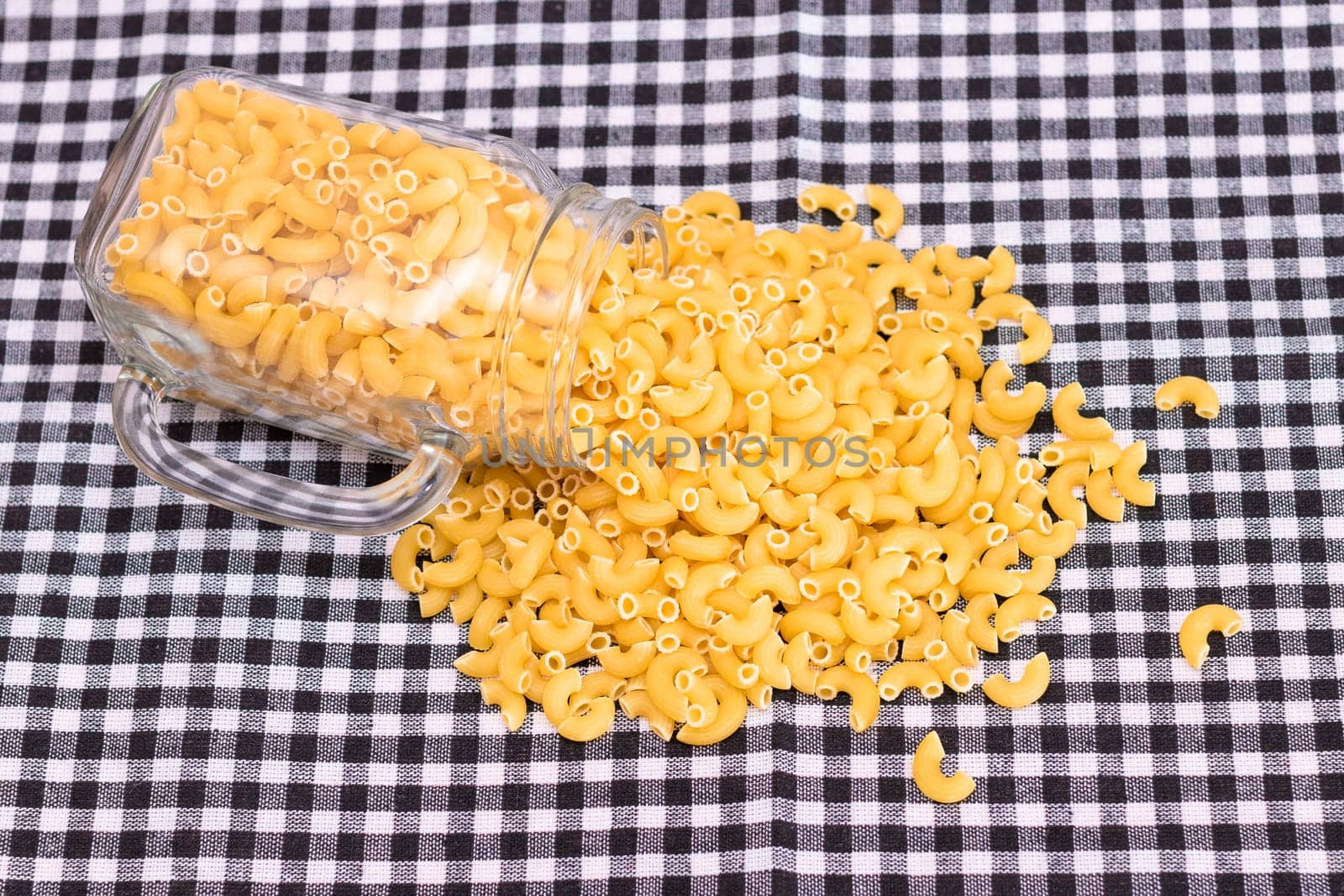 Scattered Uncooked Chifferi Rigati Pasta on Black Checkered Towel. Fat and Unhealthy Food. Classic Dry Macaroni. Italian Culture and Cuisine. Raw Pasta