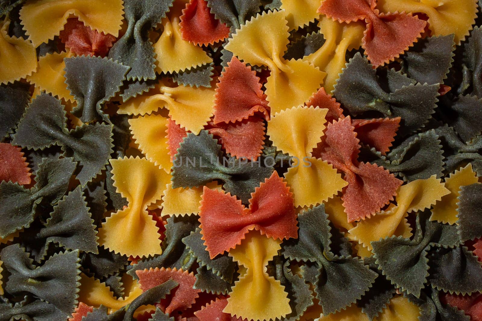 Dry Uncooked Colored Farfalle Pasta and Raw Macaroni on a Textured Background by InfinitumProdux
