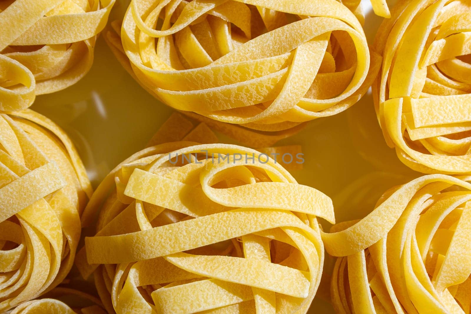 Uncooked Egg-Based Fettuccine Pasta: A Culinary Canvas of Ribbon-Shaped Macaroni, Creating a Lively and Textured Background for Gourmet Cooking. Dry Pasta. Raw Macaroni - Top View, Flat Lay