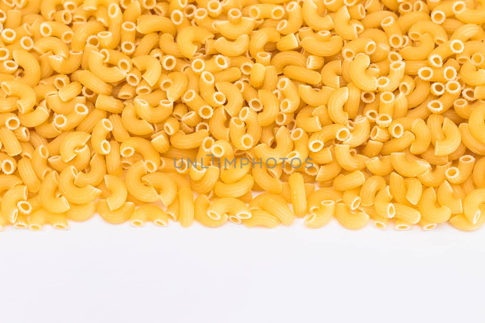 Uncooked Chifferi Rigati Pasta Scattered on White Table by InfinitumProdux