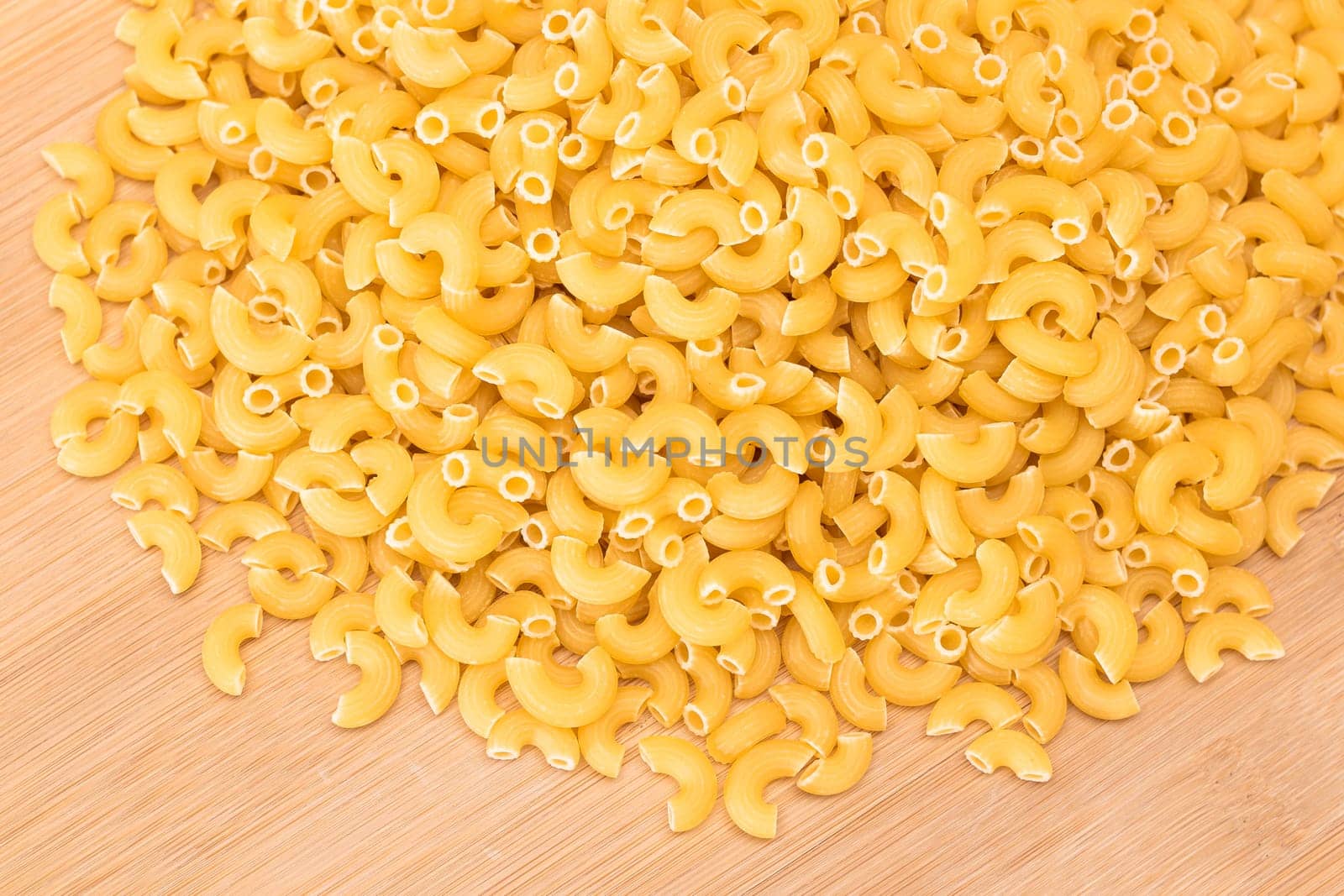 A Heap of Uncooked Chifferi Rigati Pasta on Wooden Kitchen Board. Fat and Unhealthy Food. Classic Dry Macaroni. Italian Culture and Cuisine. Raw Pasta