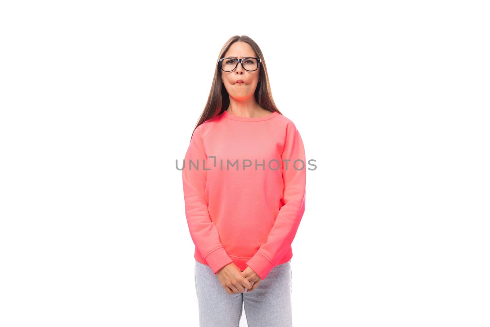 young excited european lady with dark long straight hair in a pink sweater on a white background with copy space.