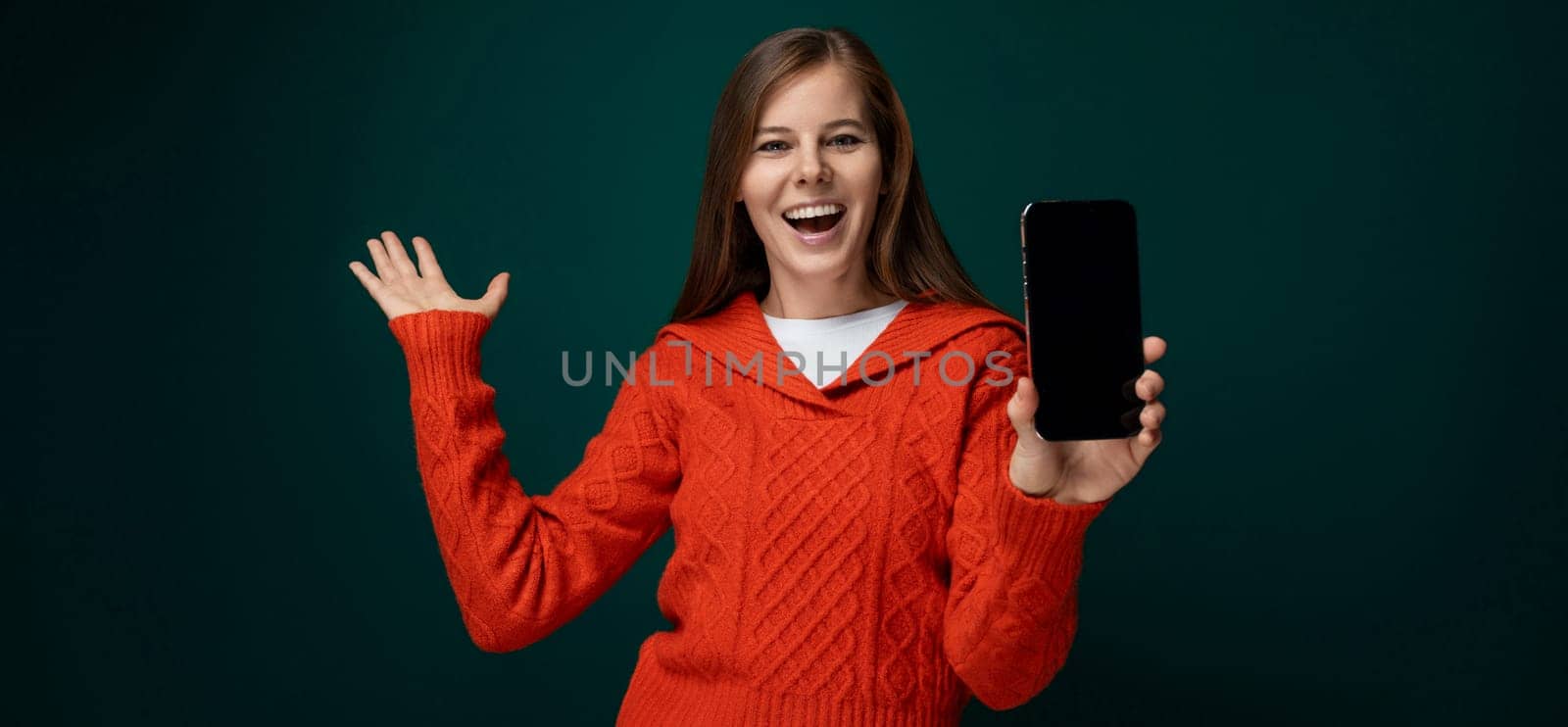 Cheerful 30 year old woman with brown hair showing off new smartphone with mockup by TRMK