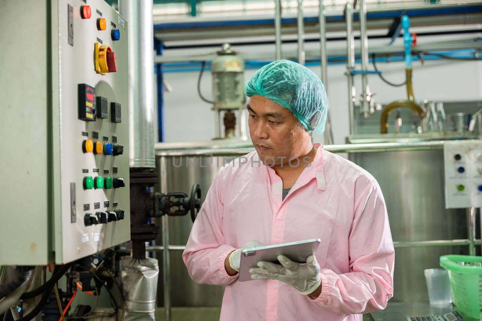 Worker using tablet in beverage factory oversees soda water filling by Sorapop