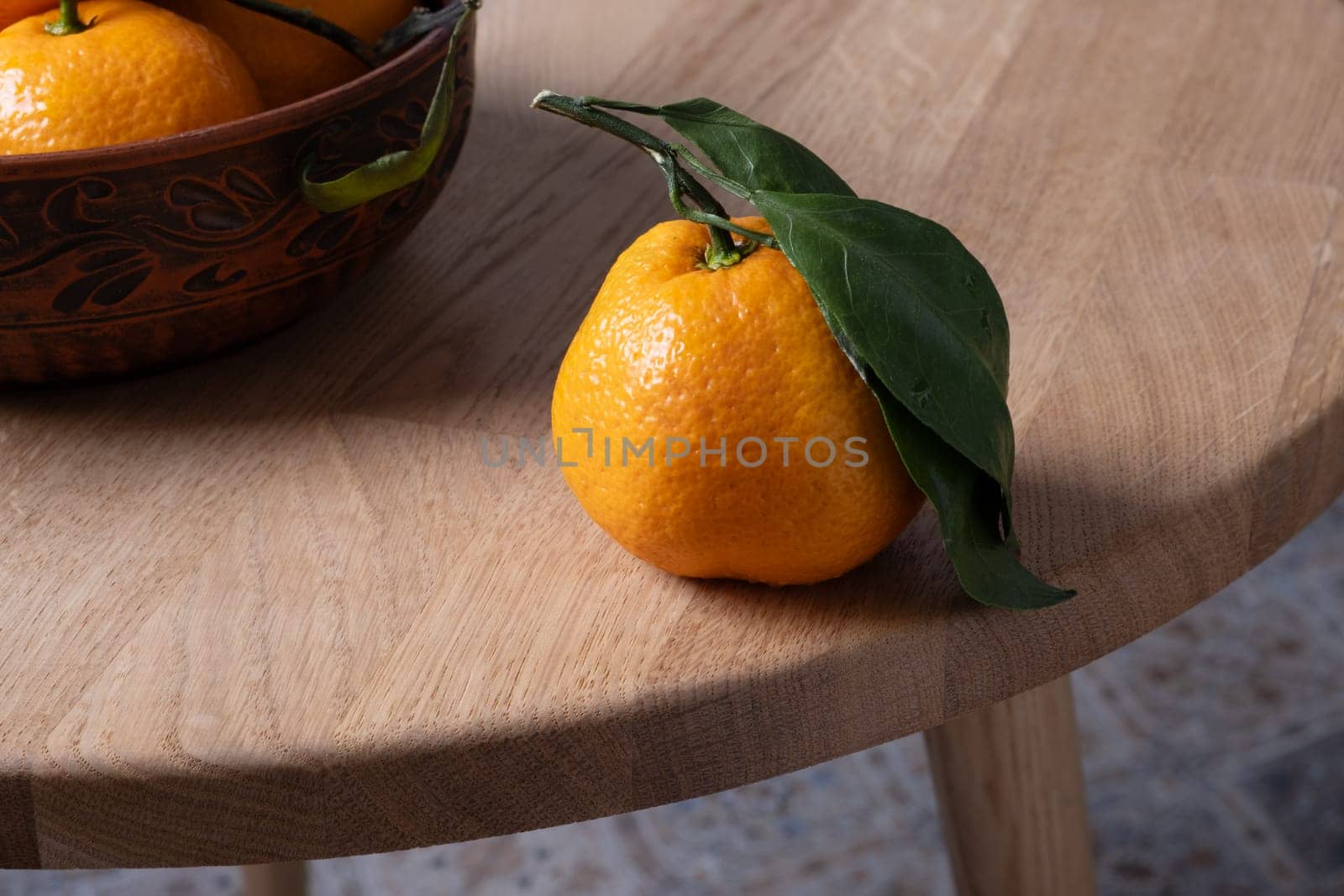 Several ripe tangerines with leaves lie on a table. Selective focus. by OlgaGubskaya