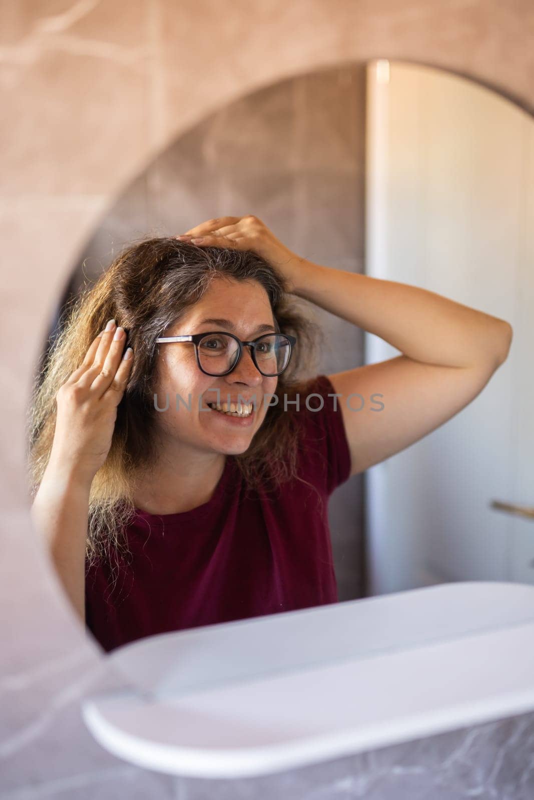 Gray haired surprised caucasian middle aged woman looking at grey hair head in mirror reflection