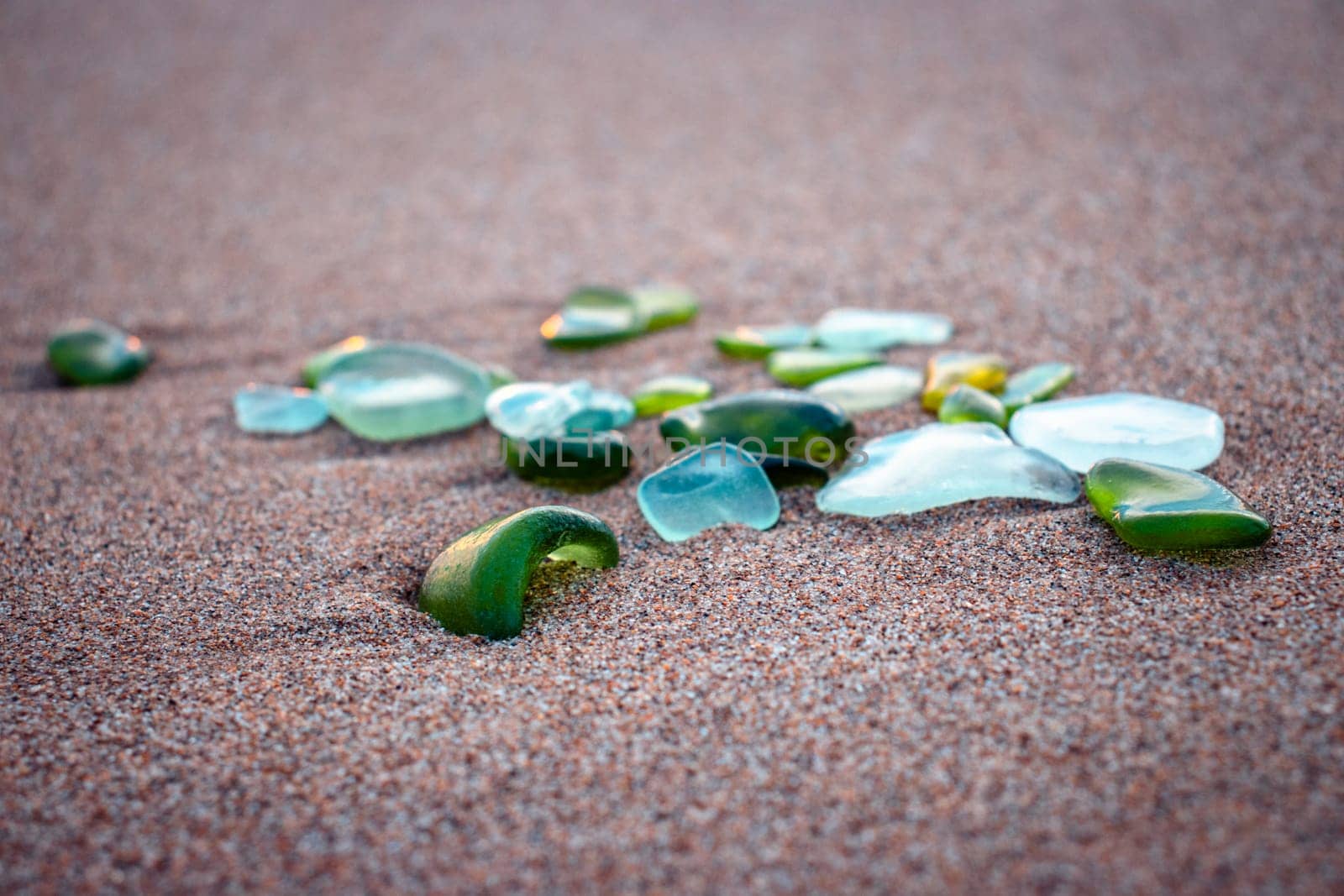 Mediterranean sea beach and glass stones photo. Glass stones from broken bottles polished by the sea. Front view photography with blurred background. High quality picture for wallpaper, travel blog