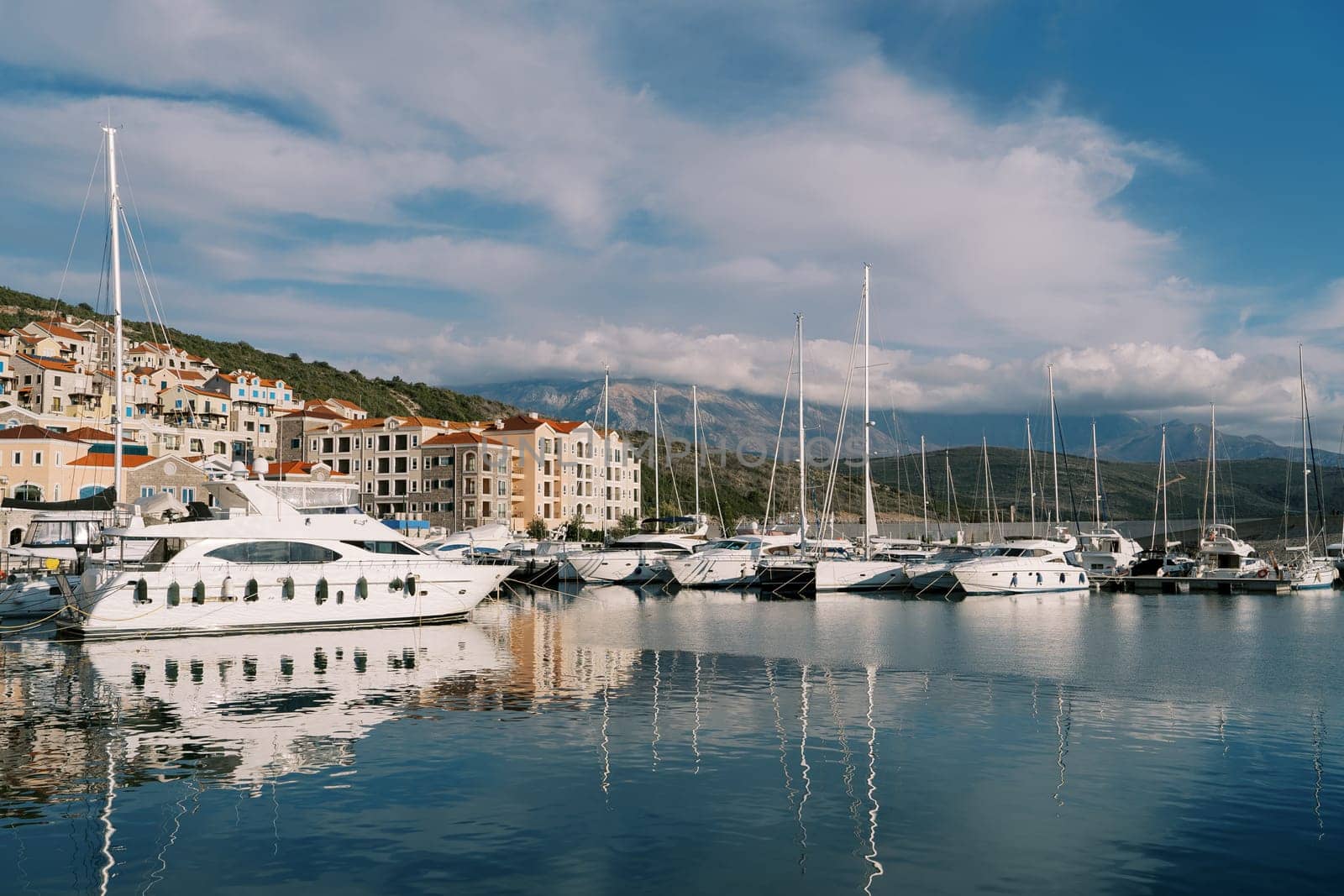 Yachts are moored at the Lustica Bay marina at the foot of the mountains. Montenegro by Nadtochiy