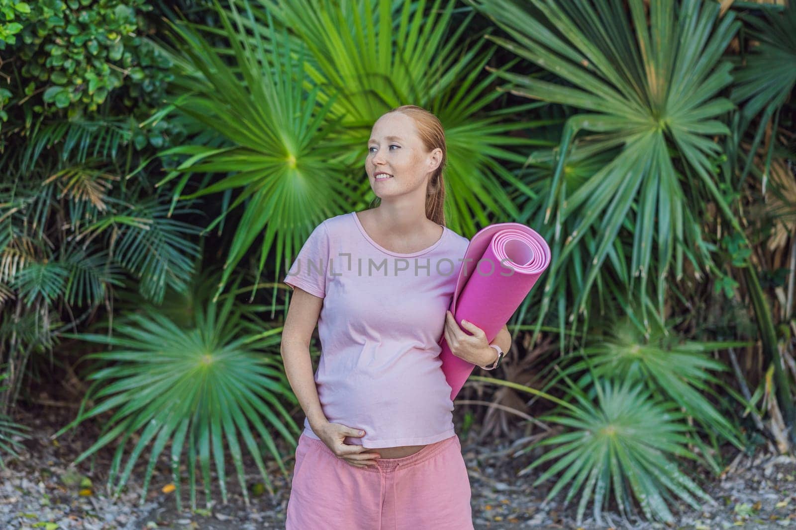 Energetic pregnant woman takes her workout outdoors, using an exercise mat for a refreshing and health-conscious outdoor exercise session by galitskaya