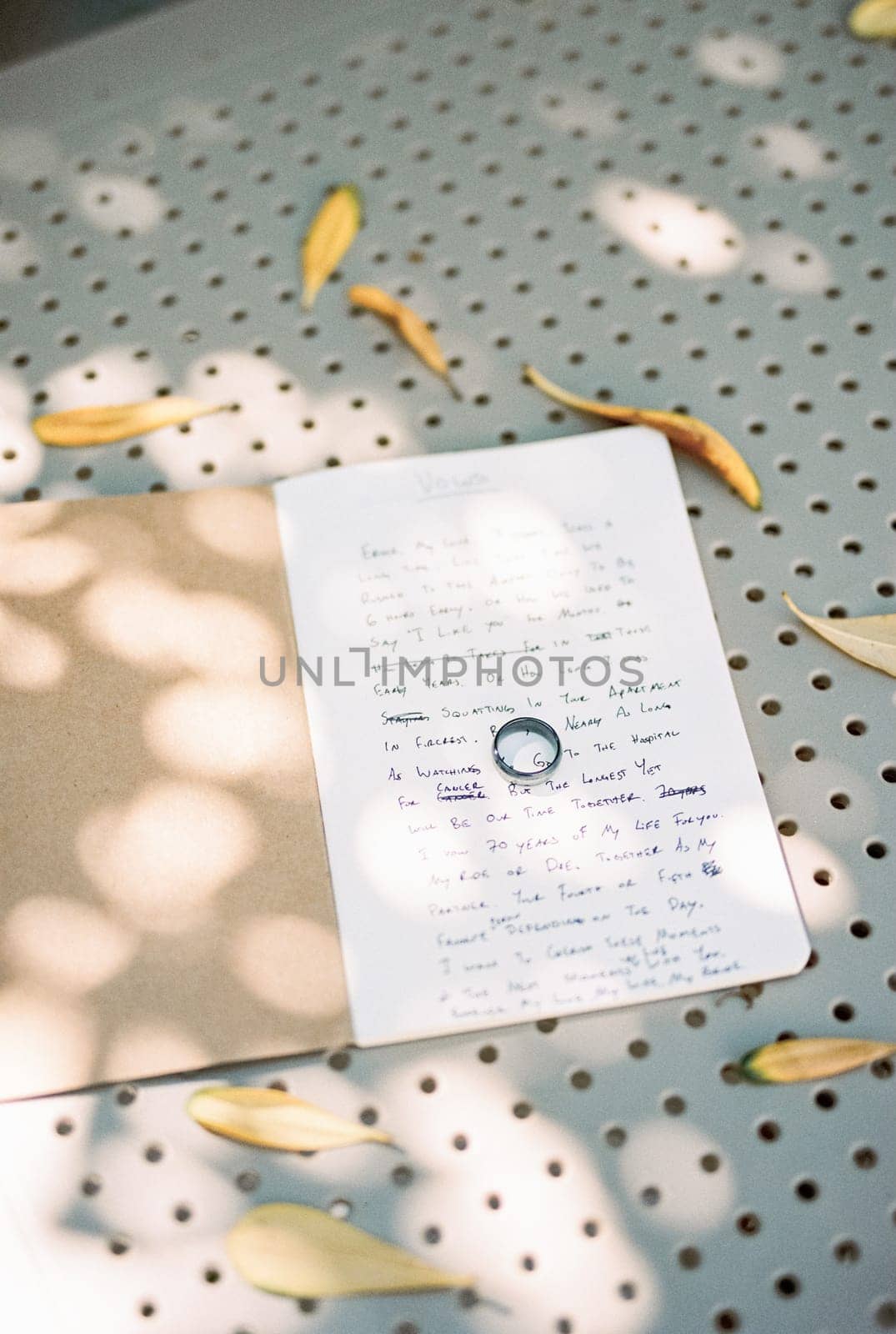 Wedding ring lies on the wedding vows in a notebook on the table among the yellow leaves by Nadtochiy