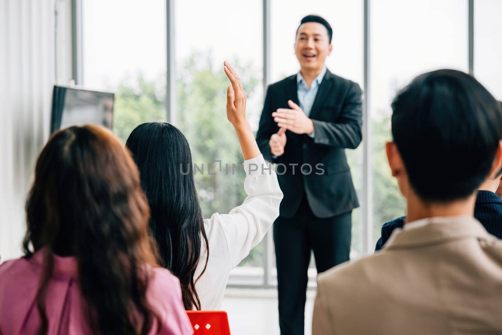 During a conference, a diverse crowd of businesspeople raises their hands to ask questions, vote, or volunteer. This scene emphasizes teamwork and active audience involvement by Sorapop