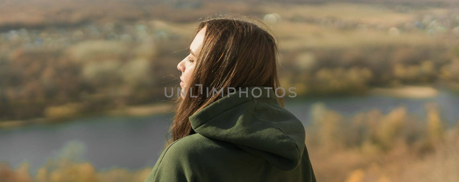 Rear view of trendy young woman in dark green hoodie in autumn banner with space for advertising. Cute model walks in park in golden autumn through colorful trees and fallen leaves copy space. Autumn fall walk colorful nature by Satura86