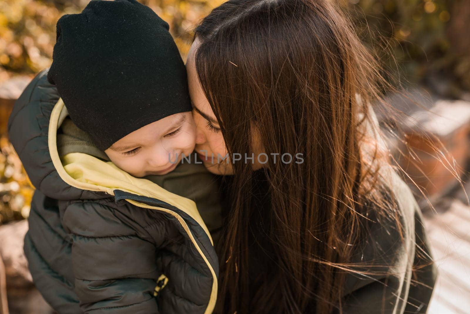 happy loving young mother kisses her toddler son on the walk.