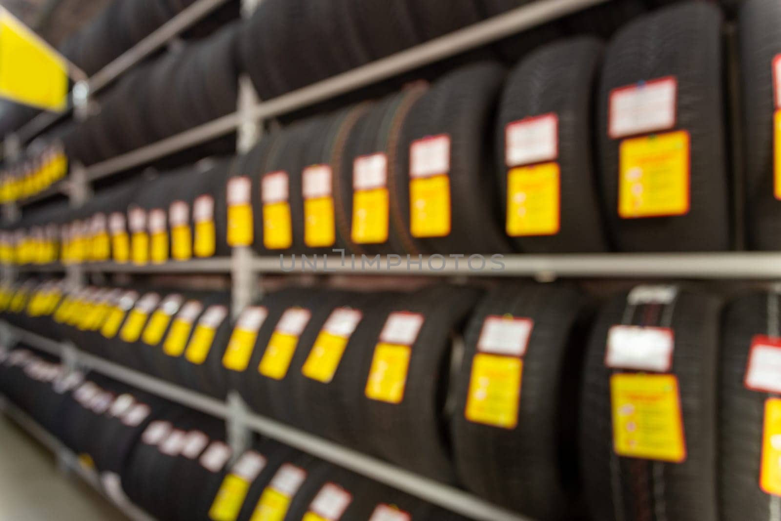 Blurred image rows of brand new tires for sale at retail store. Defocused background interior of auto and tire trading store. Transportation services concept. Vintage tone.
