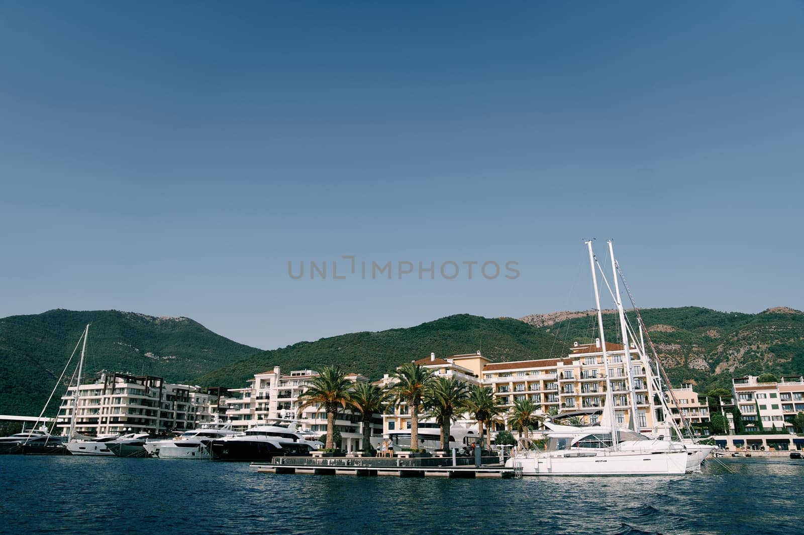 Motor yachts are moored along the pier opposite the Regent Hotel. Porto, Montenegro by Nadtochiy