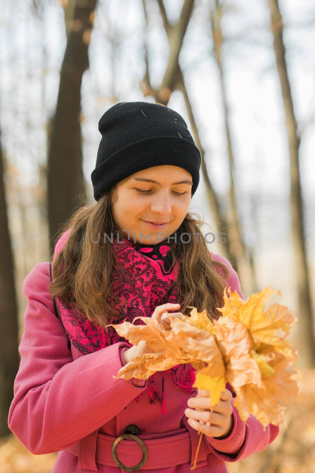 Portrait of beautiful happy young woman in pink jacket holding bouquet of yellow leaves at autumn park. Pretty Caucasian lady smiling and looking at camera during her walk outdoors. Generation Z and gen z youth by Satura86