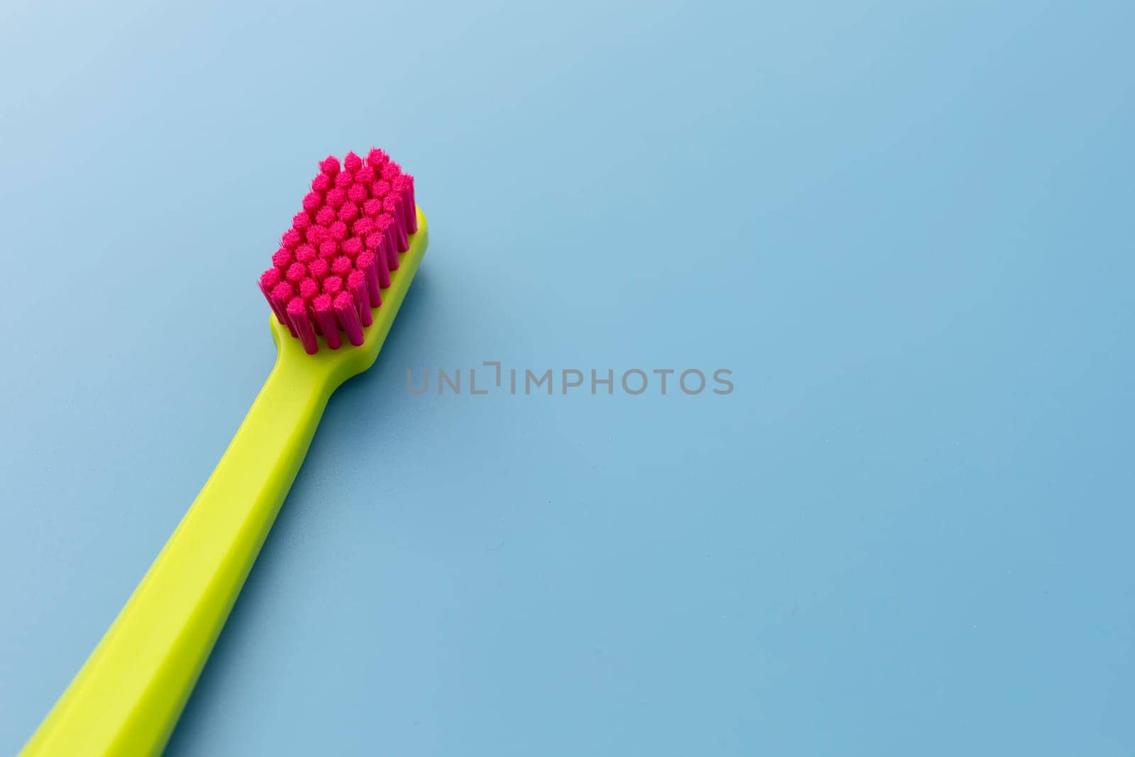 Flat Lay Mockup Green Toothbrush with Pink Bristles Lying On Blue Background, Copy Space For Tex. Morning hygiene, Bathroom accessories. Dental Health Care Template. Horizontal Top View Plane.