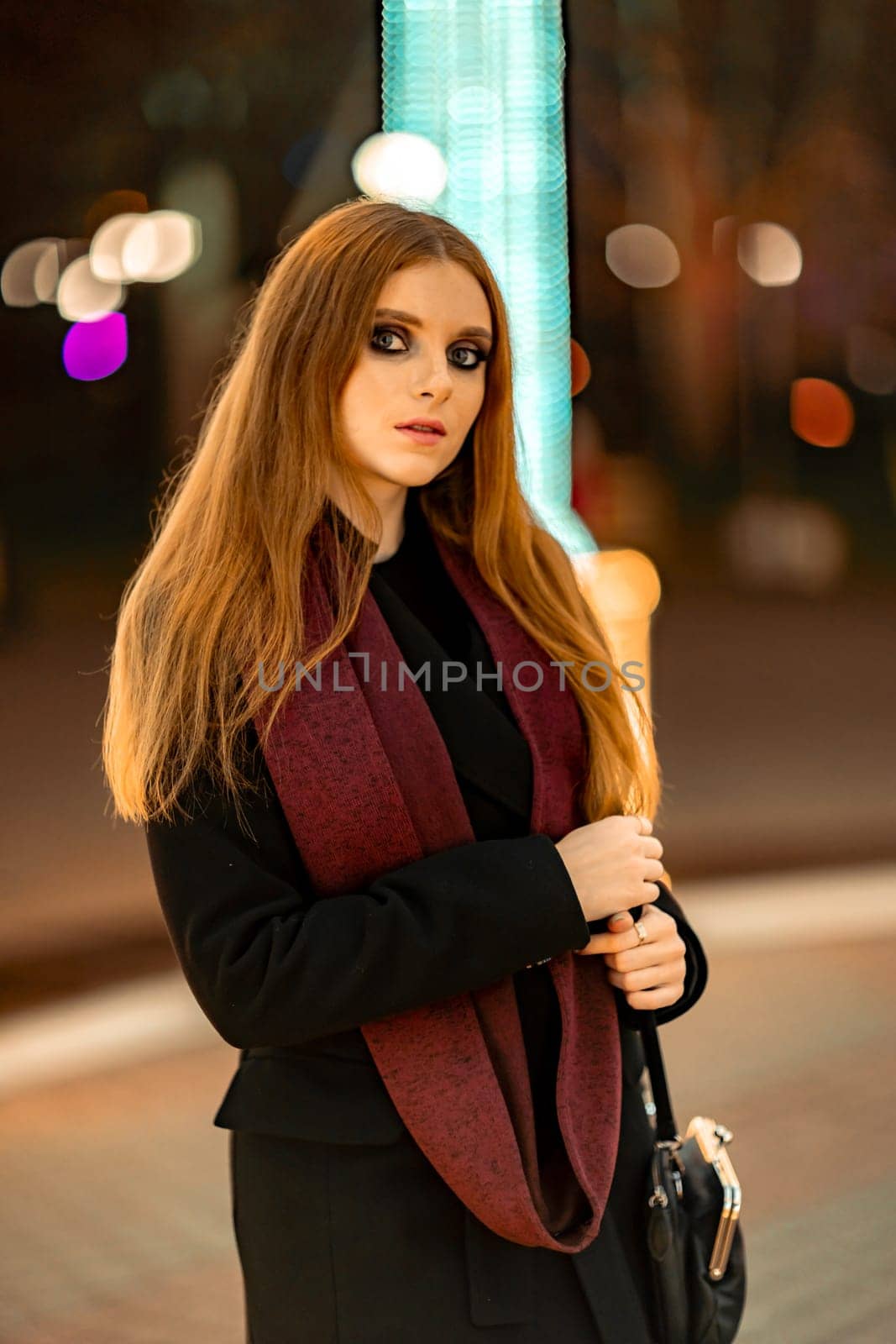 Christmas mood. Woman with long hair in sity decorated for Christmas. She is dressed in a black coat