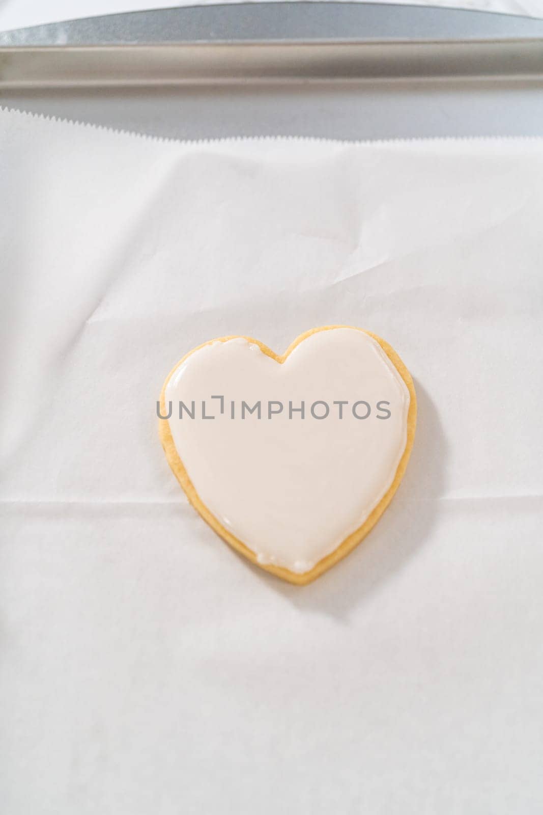 Decorating heart-shaped sugar cookies with pink and white royal icing for Valentine's Day.