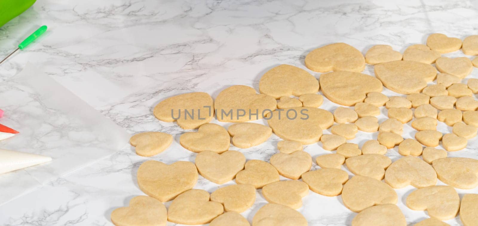 Decorating heart-shaped sugar cookies with pink and white royal icing for Valentine's Day.