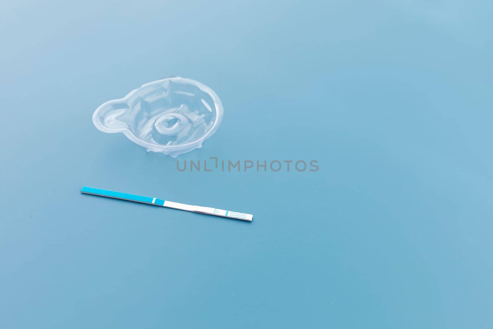 Mockup Ovulation Urine Test Strip with Cup on Blue Background, Copy Space For Text. Pregnancy stick test Template. Pregnancy, Childbirth. Home-use Test Kit to Measure Luteinizing. Horizontal Plane.