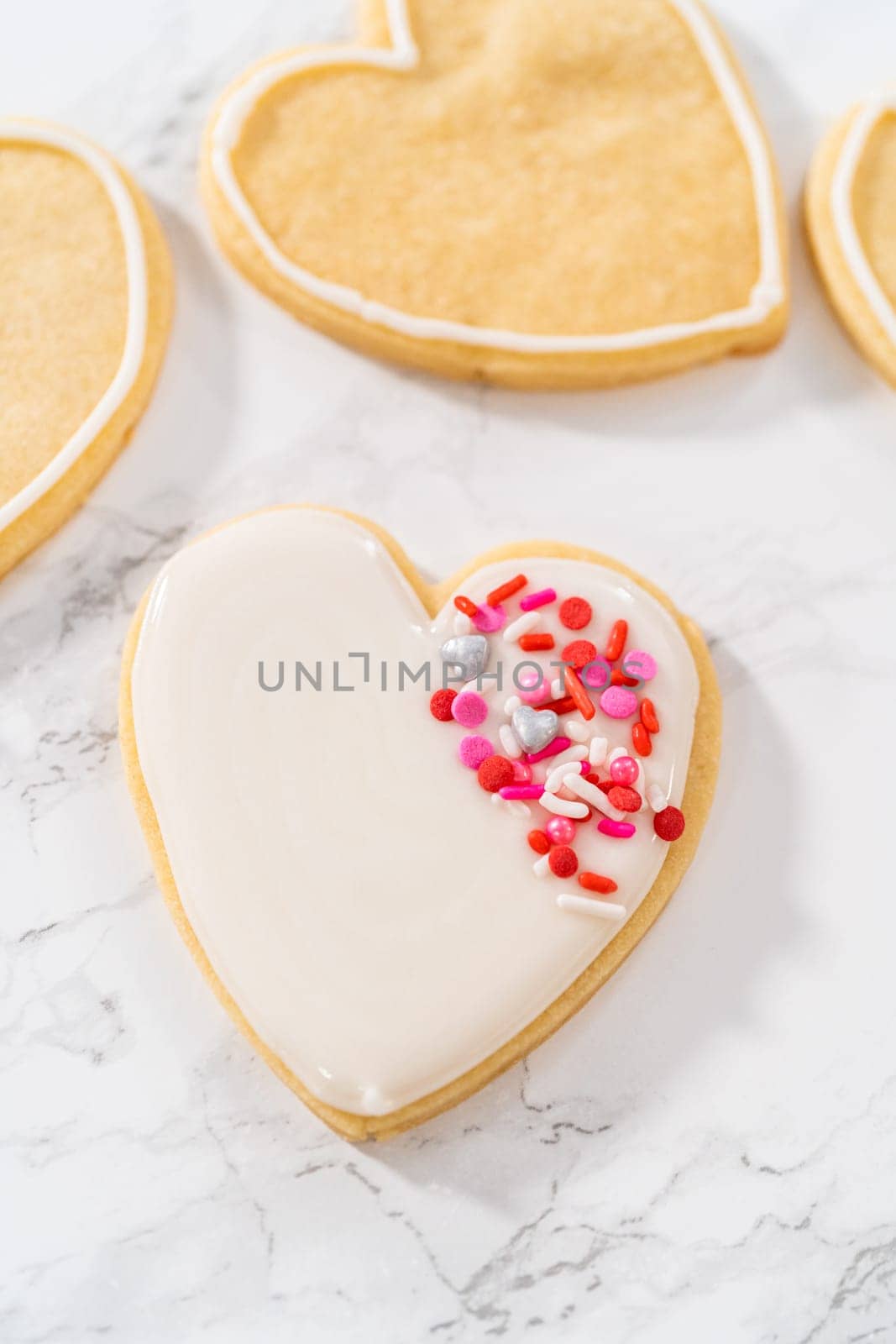 Decorating heart-shaped sugar cookies with pink and white royal icing for Valentine's Day.