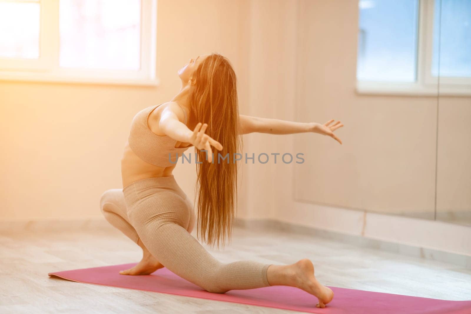 Girl does yoga. Young woman practices asanas on a beige one ton background. by Matiunina