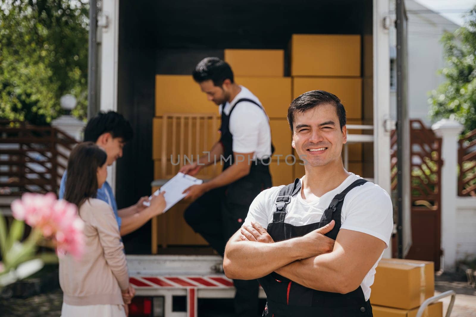 In a portrait a happy mover unloads boxes from a truck into a new home. These workers show teamwork ensuring a smooth relocation and happiness. Moving day concept
