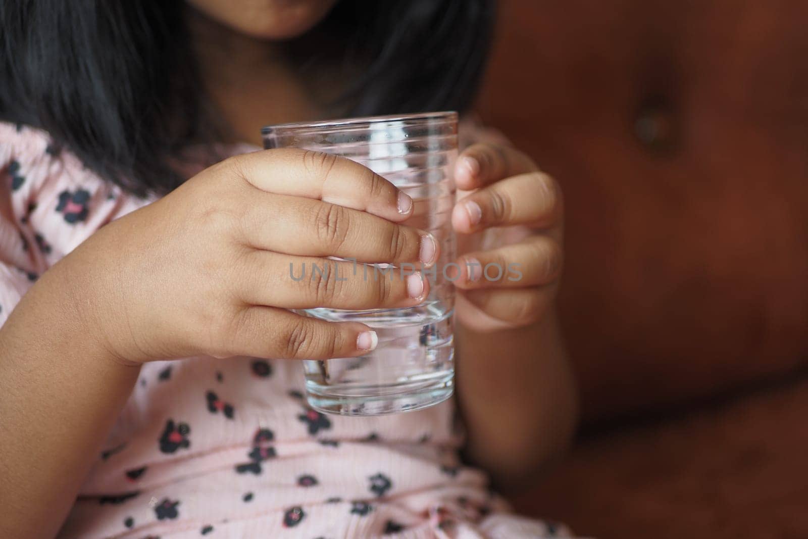 child hand holding a glass of water .