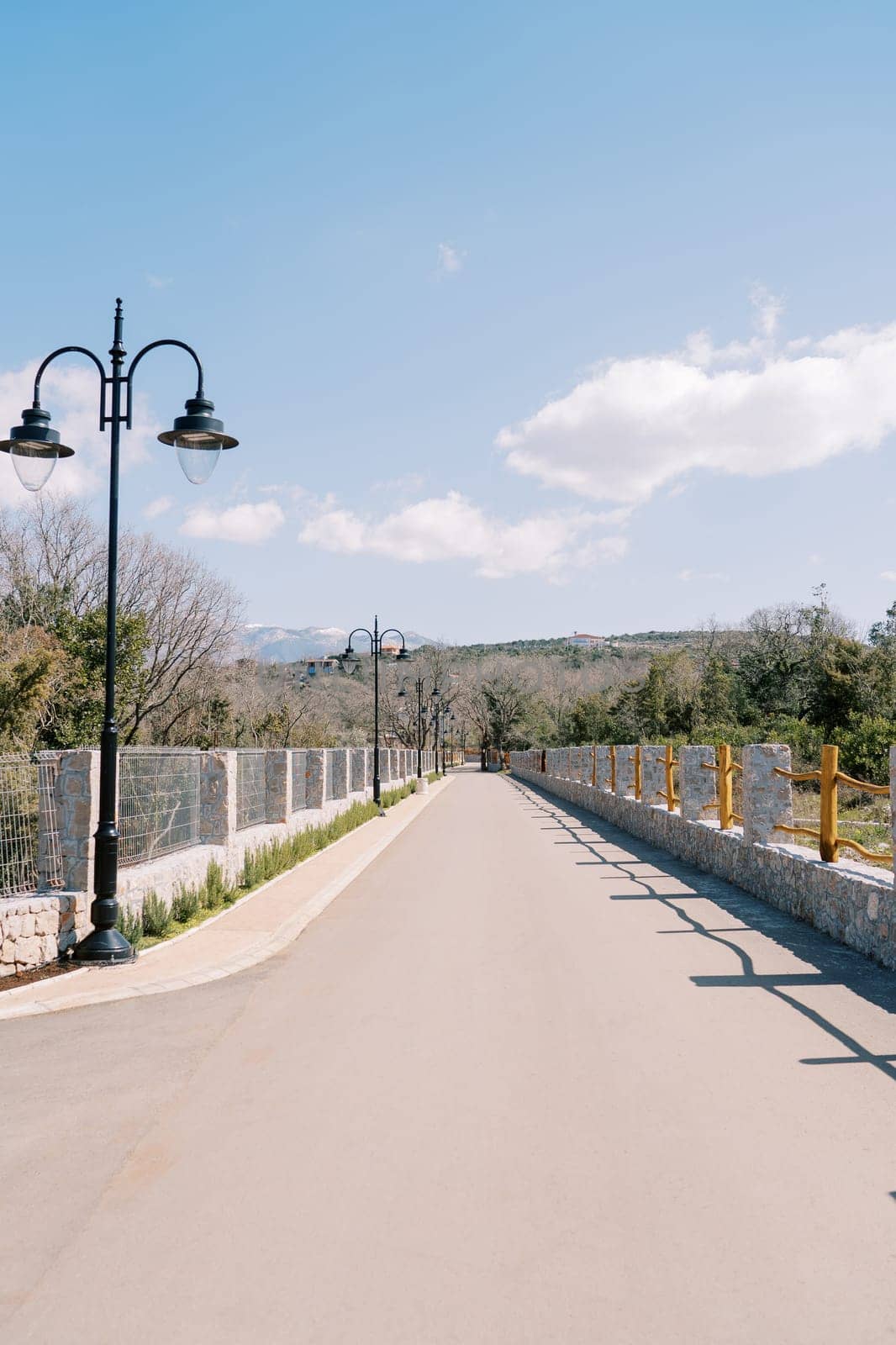 Asphalt road in a green park with a fence at the foot of the mountains. High quality photo