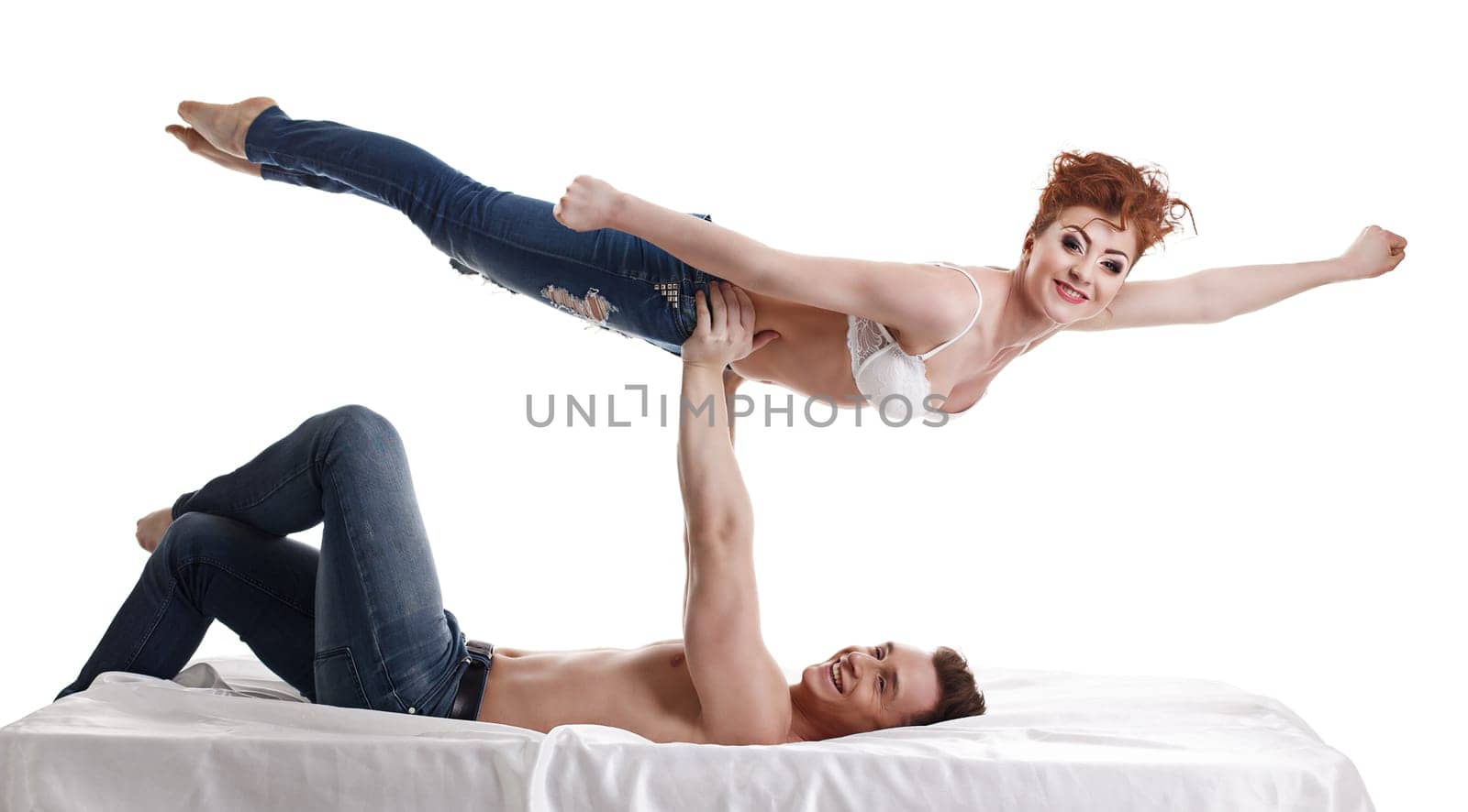 Cheerful young people perform acrobatic stunt in bed