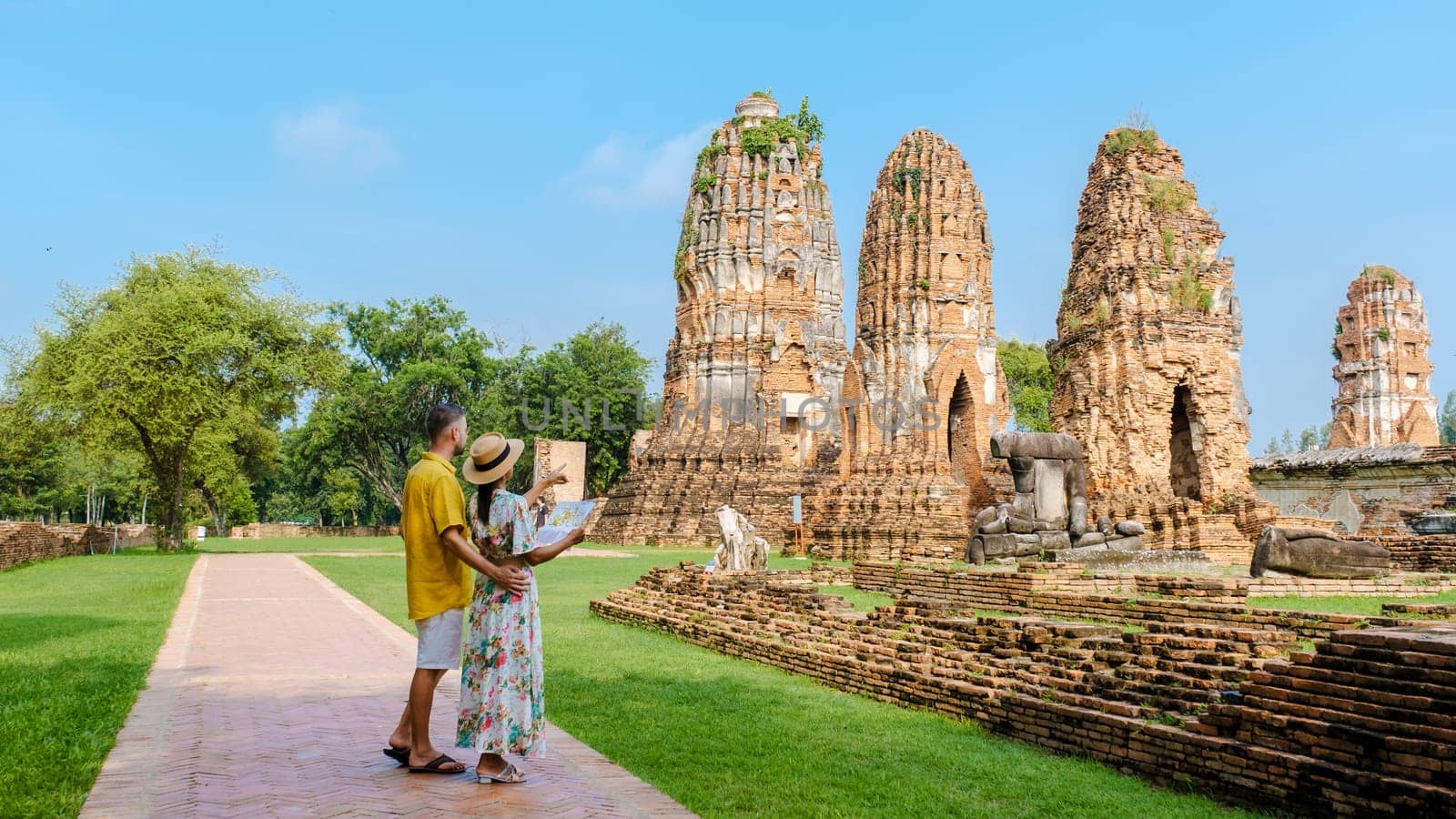 Ayutthaya Thailand at Wat Mahathat, a couple of men and women with a hat and tourist maps visiting Ayutthaya Thailand. Tourists with a map in is hand looking at a temple in Thailand